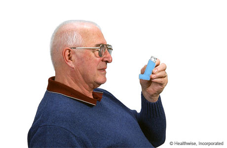 A man holding the inhaler upright